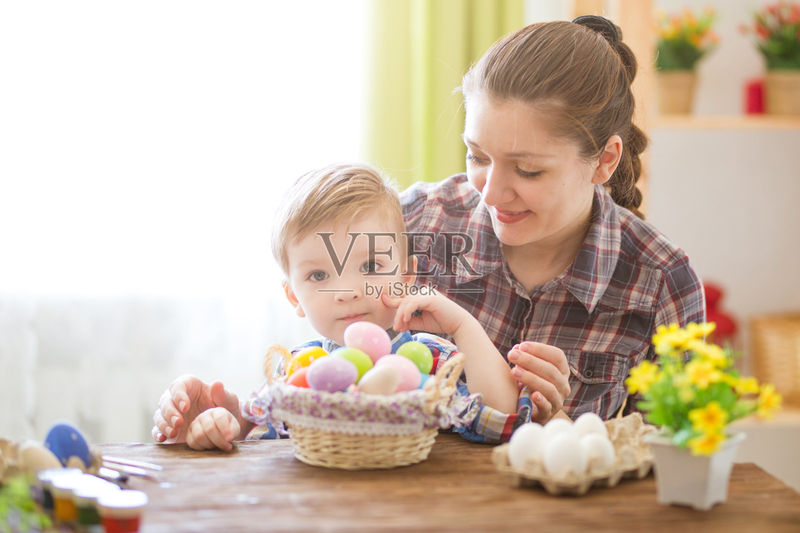 画复活节彩蛋时的快乐时光。复活节的概念。快乐的妈妈和她可爱的孩子正在为复活节画彩蛋照片摄影图片