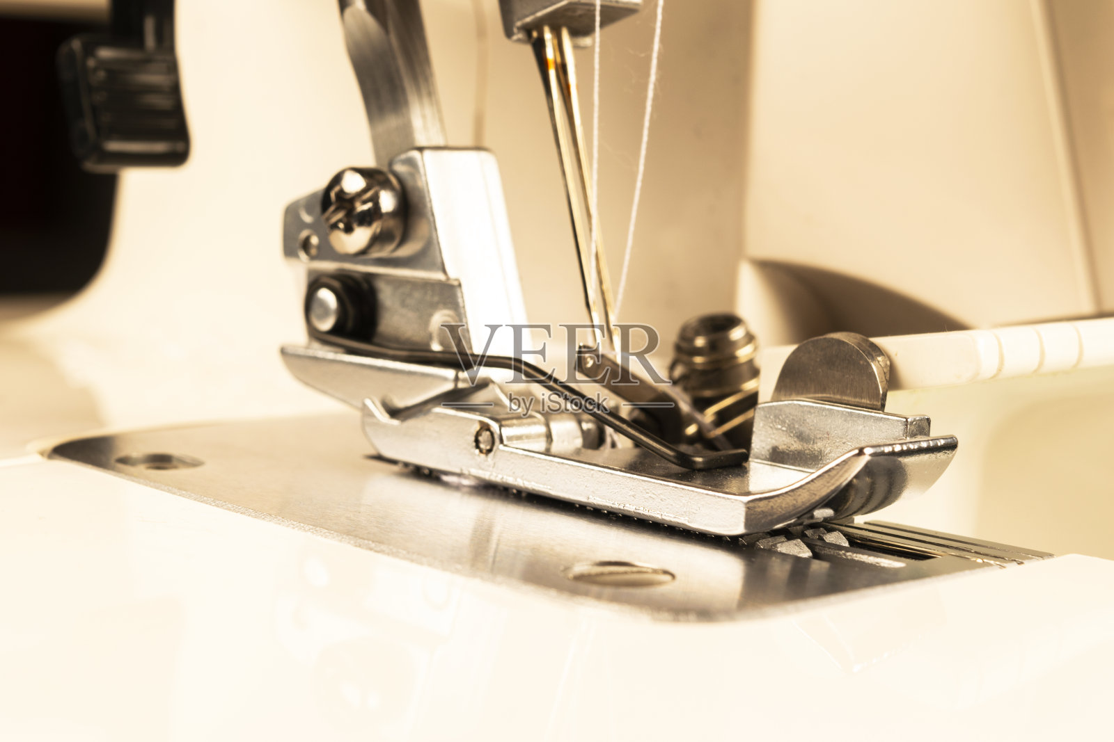 缝纫机的压脚，针线闭合。缝纫机的细节。缝纫机的脚上有一根针。生产线缝纫机。针和脚的细节。照片摄影图片