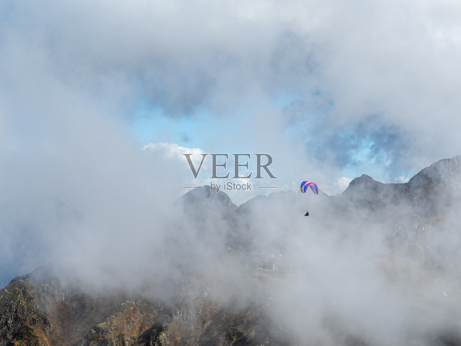 滑翔伞穿过云雾飞越群山照片摄影图片