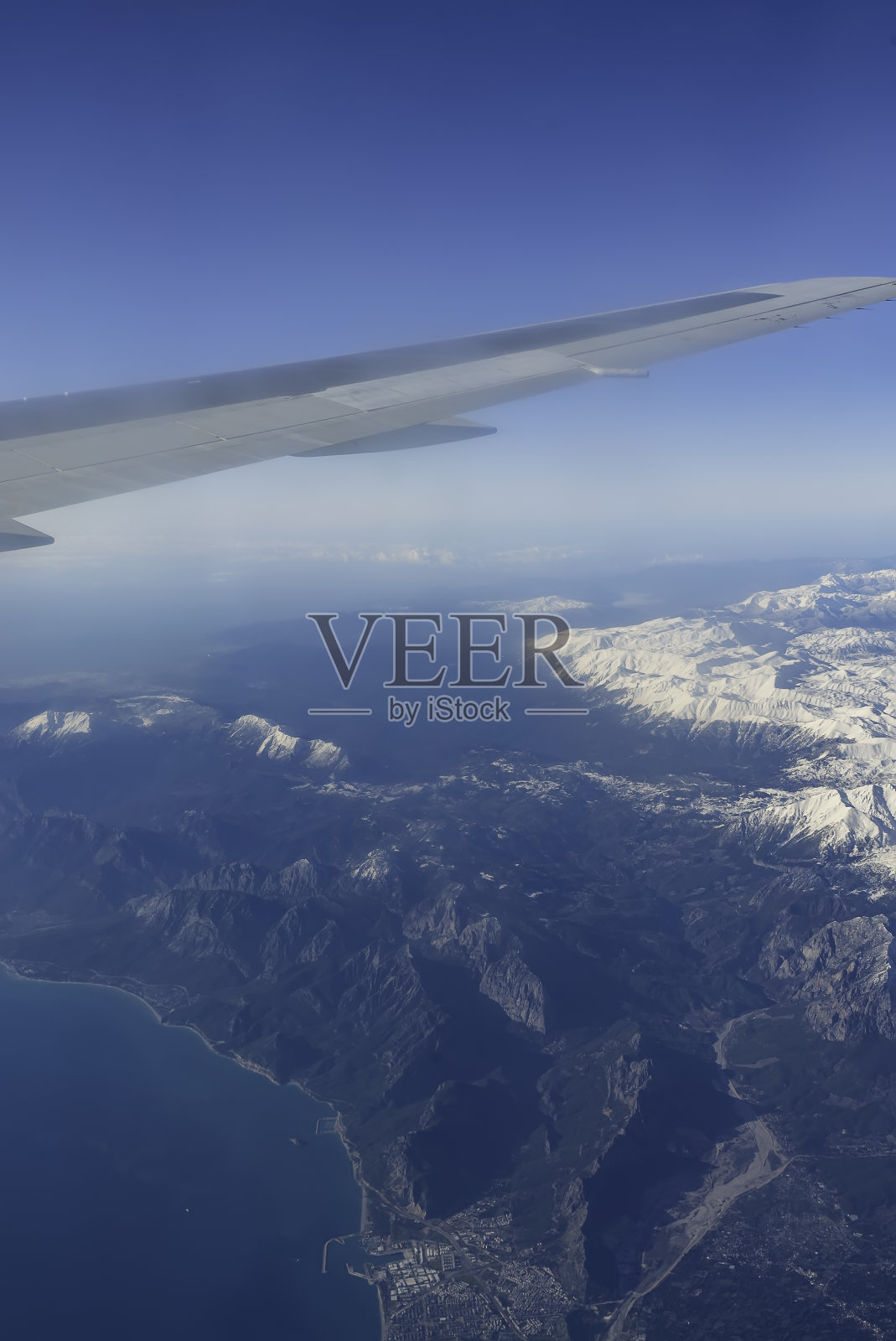 冬天的山从飞机窗口与飞机机翼。土耳其山脉景观鸟瞰图。雪的山峰。照片摄影图片