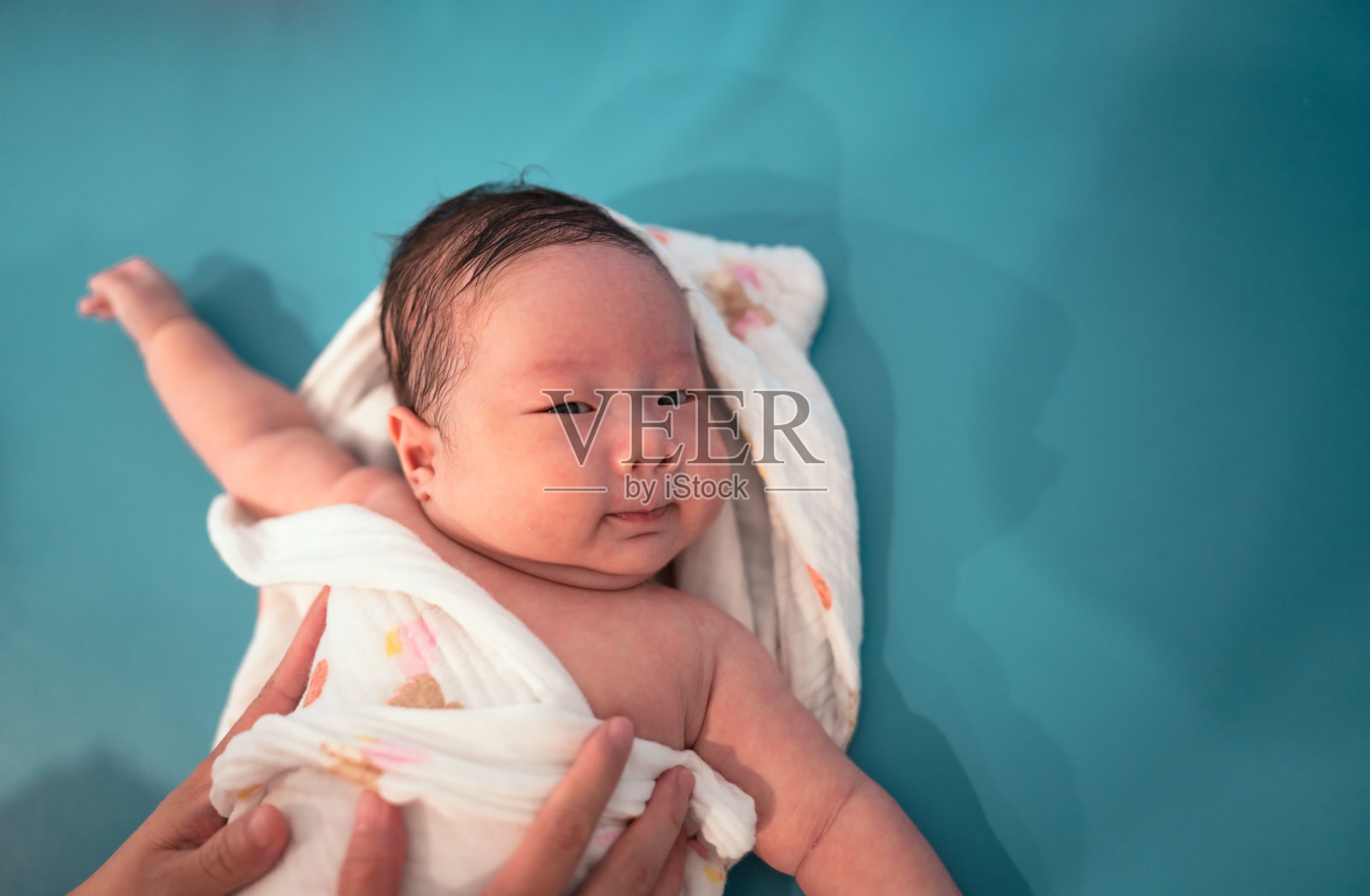 可爱的新生男婴沐浴后用毛巾用母亲的双手轻轻擦干身体照片摄影图片