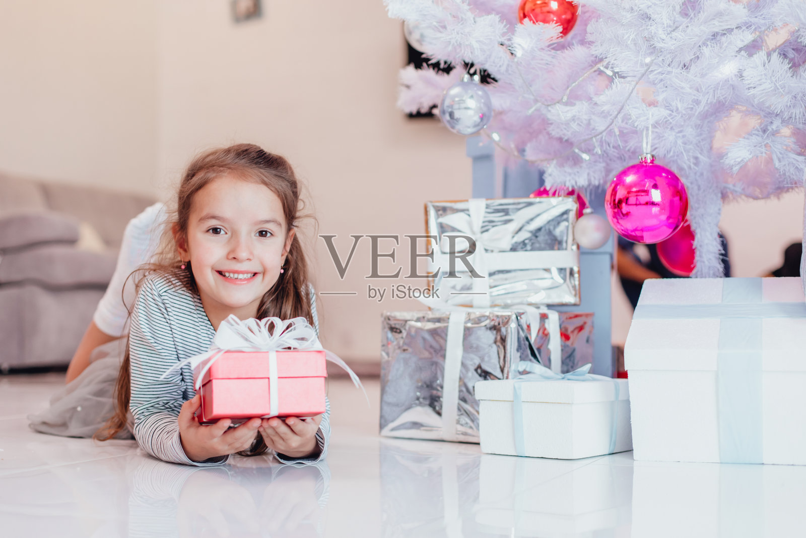 粗心，微笑的小女性享受圣诞时间和礼物。照片摄影图片