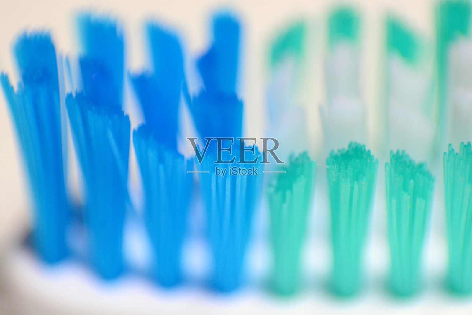 靠近蓝色、绿色和白色的牙刷，牙刷以白色为背景，选择性聚焦照片摄影图片