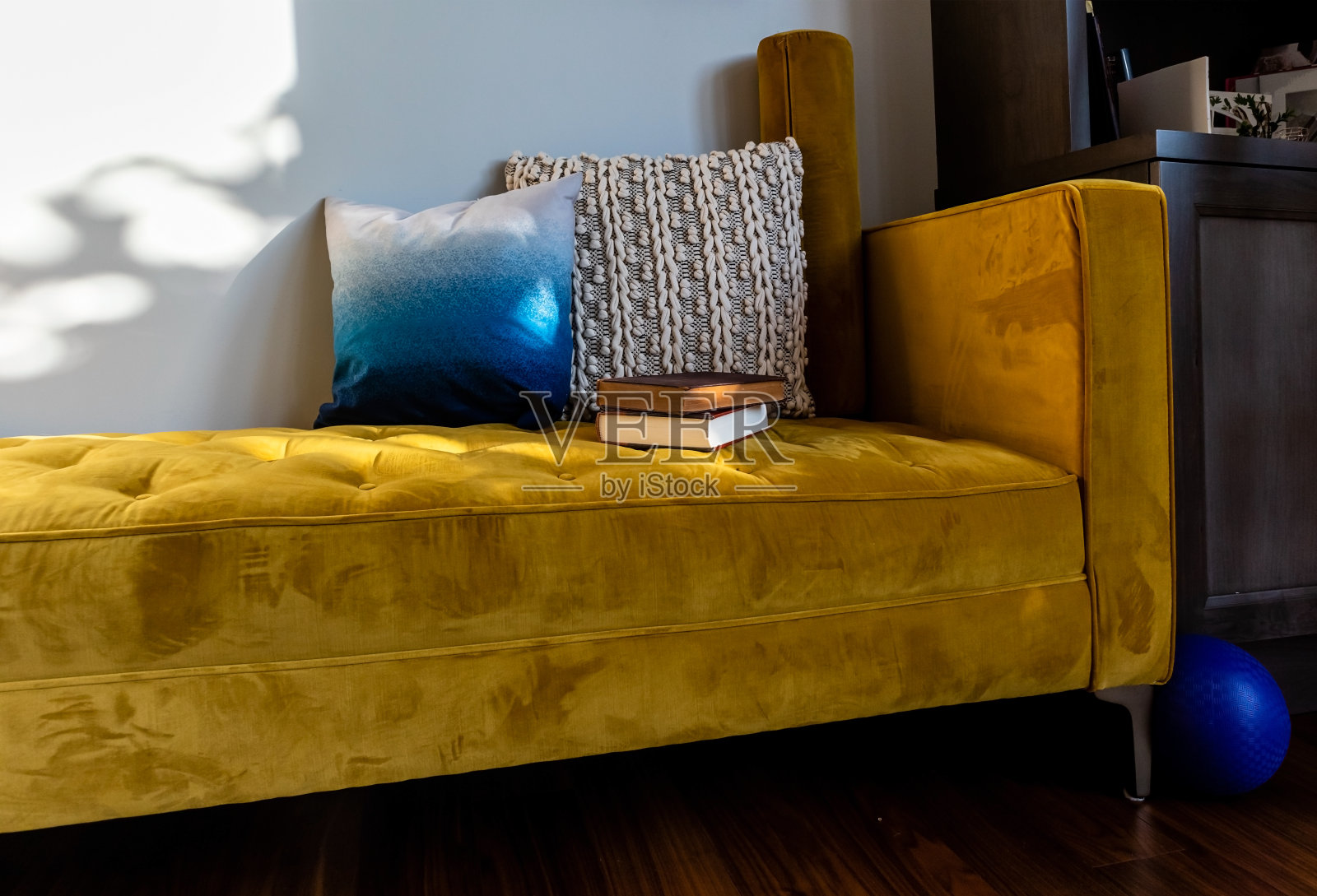 黄色的沙发上放着书籍、阳光和五颜六色的靠垫照片摄影图片