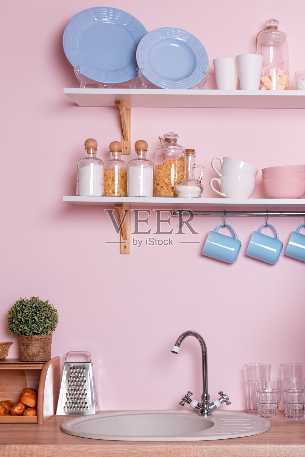 粉色和蓝色粉彩现代厨房室内。厨房配件，谷物容器，盘子和挂蓝色杯子。照片摄影图片