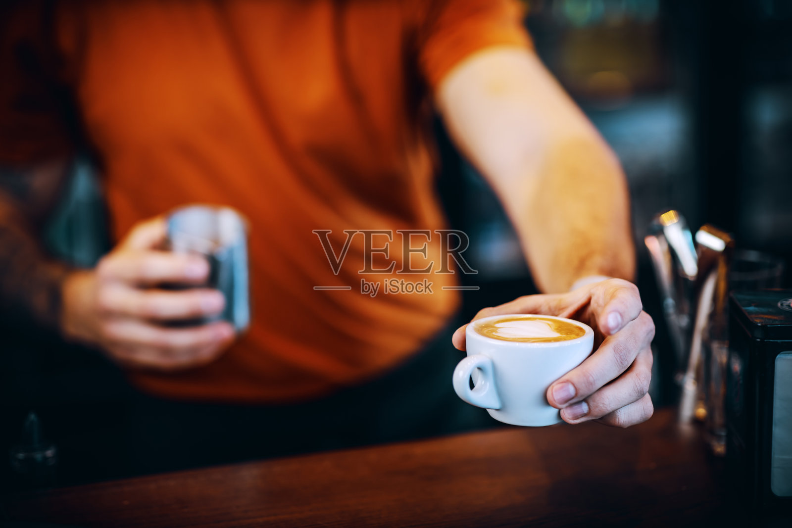 近距离的酒吧招待拿着一杯新鲜的咖啡早上，并把它给顾客。照片摄影图片