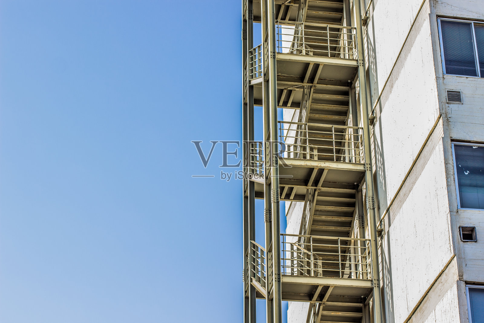 金属防火逃生楼梯建筑室外一侧的高层建筑和空旷的蓝天，复制空间照片摄影图片