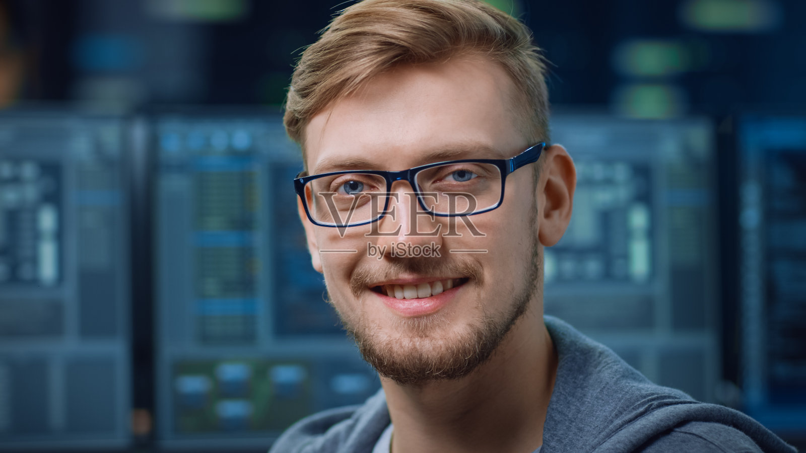 一个聪明和英俊的IT专家的肖像戴眼镜微笑在相机。技术研究数据中心带屏幕的无焦点个人电脑照片摄影图片