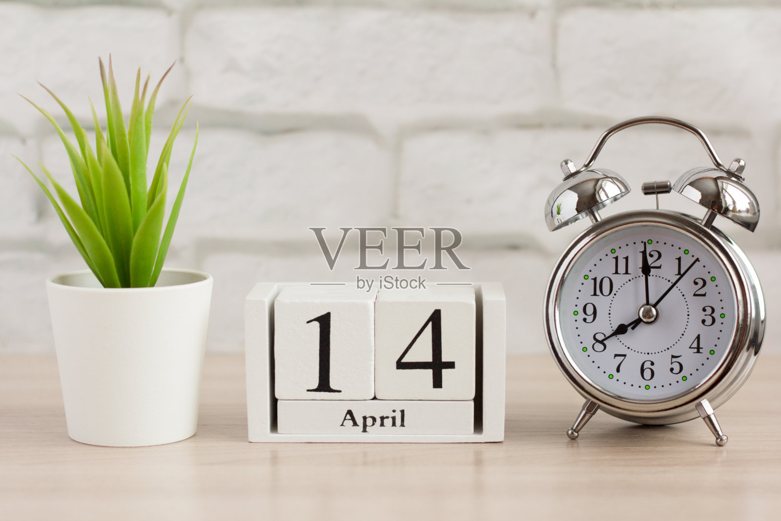 在4月14日的一个木制日历旁边的闹钟。日历日期，节日事件，或生日照片摄影图片