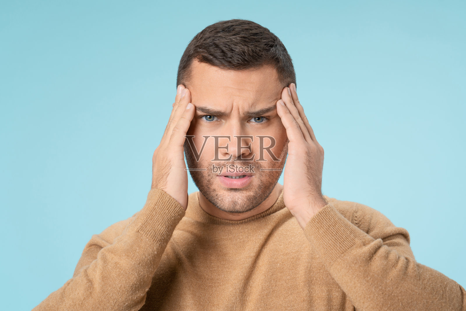 近距离观察白人不健康的男性遭受强烈的头痛和疲劳孤立在蓝色的工作室背景照片摄影图片