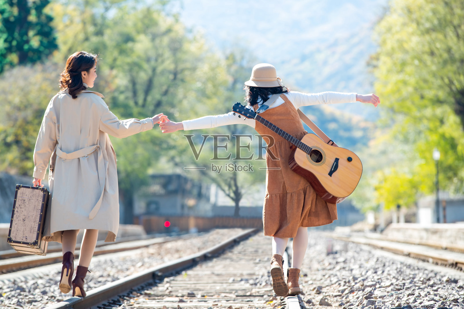 青年闺蜜手牵手走在铁轨上照片摄影图片