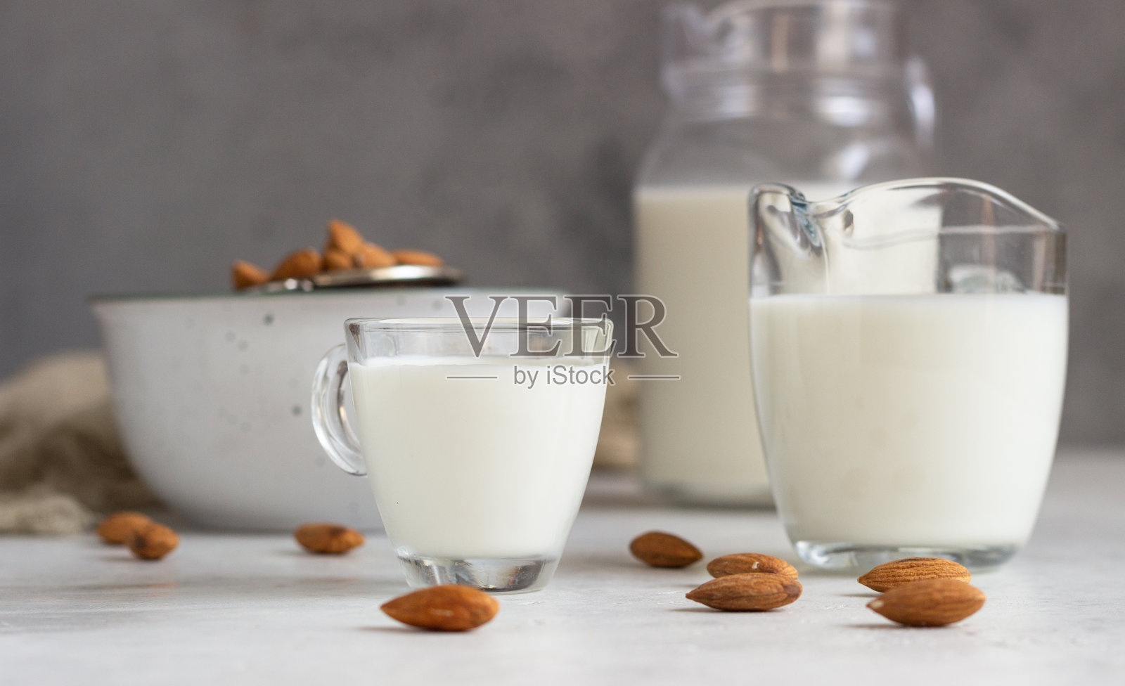 有机杏仁牛奶在玻璃罐和原料在浅灰色的背景。健康的素食饮食。替代类型的牛奶。照片摄影图片