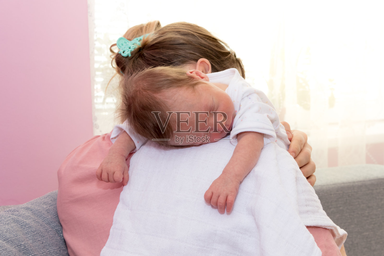 快乐的小女孩睡在妈妈的肩膀上。照片摄影图片