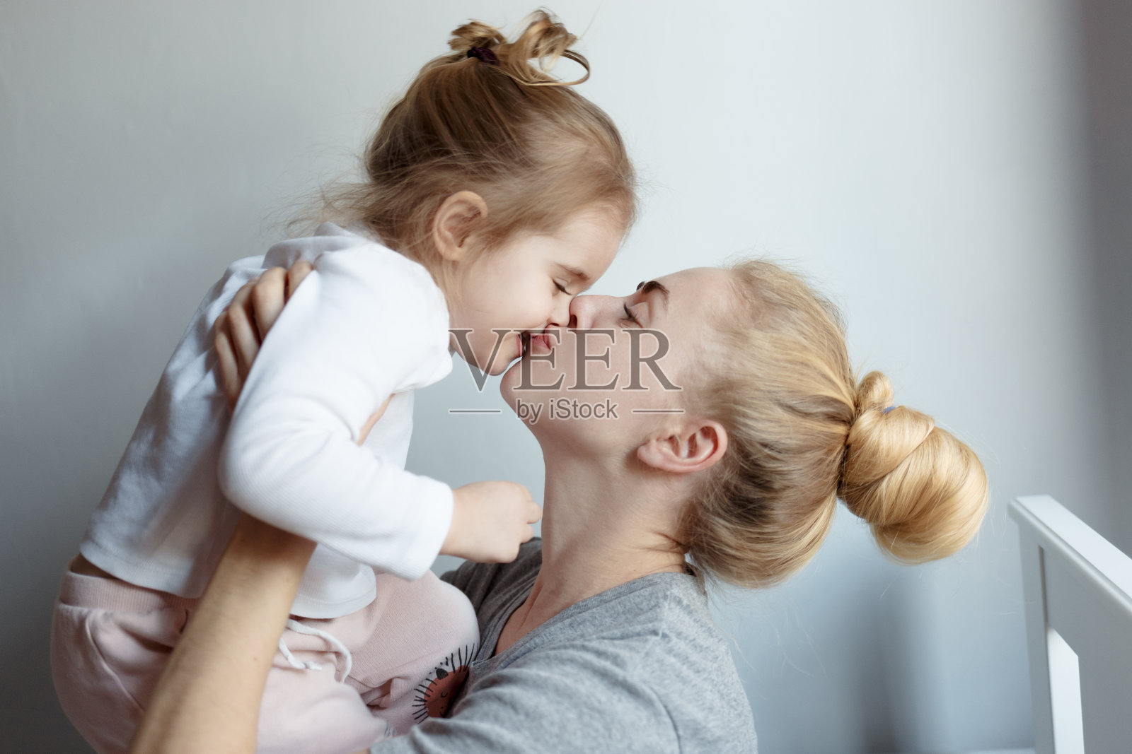 快乐妈妈拥抱、亲吻笑着的女儿，把她抱在怀里。家庭,母亲的概念照片摄影图片