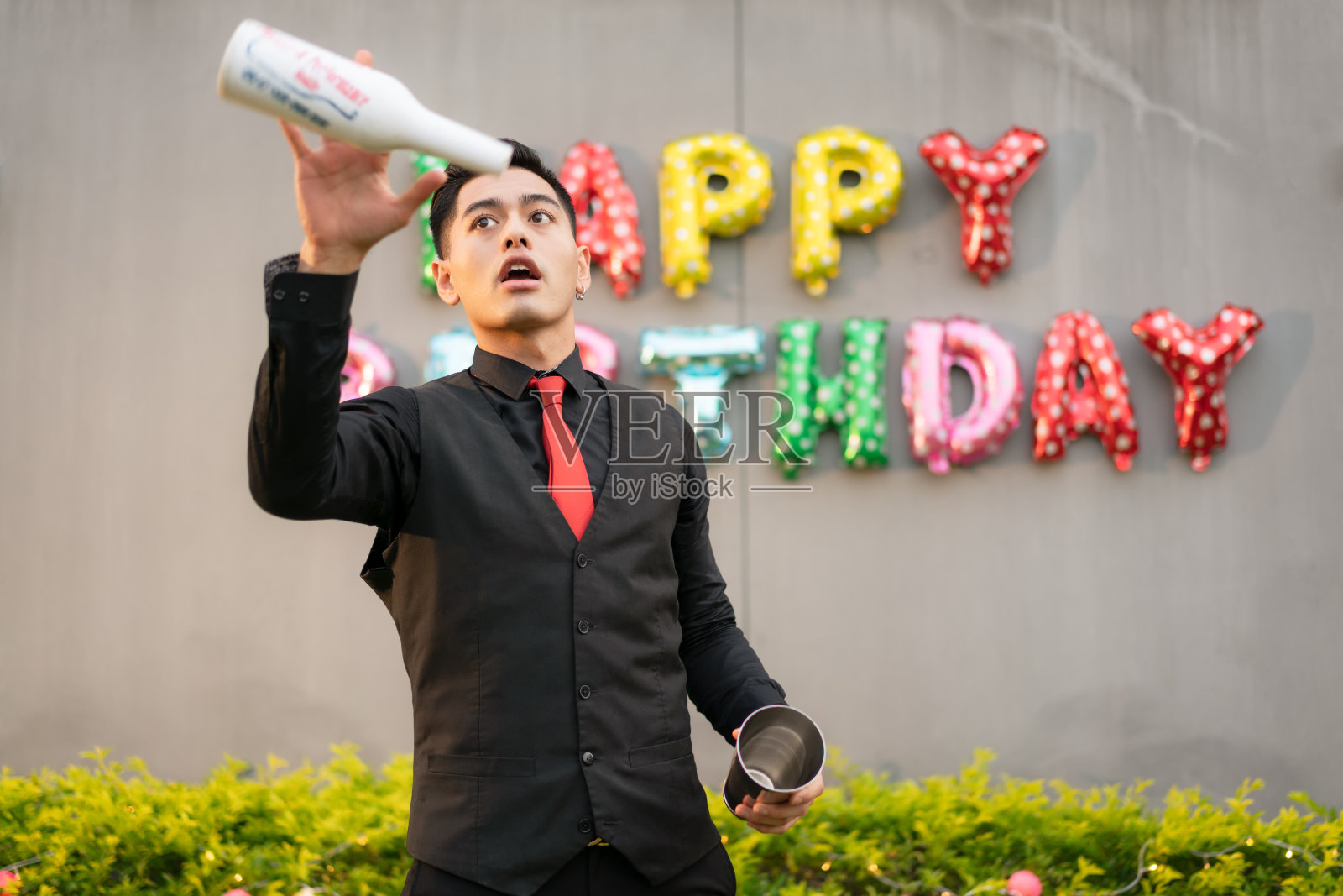 年轻的亚洲酒保正在练习在生日派对上扔瓶子。照片摄影图片