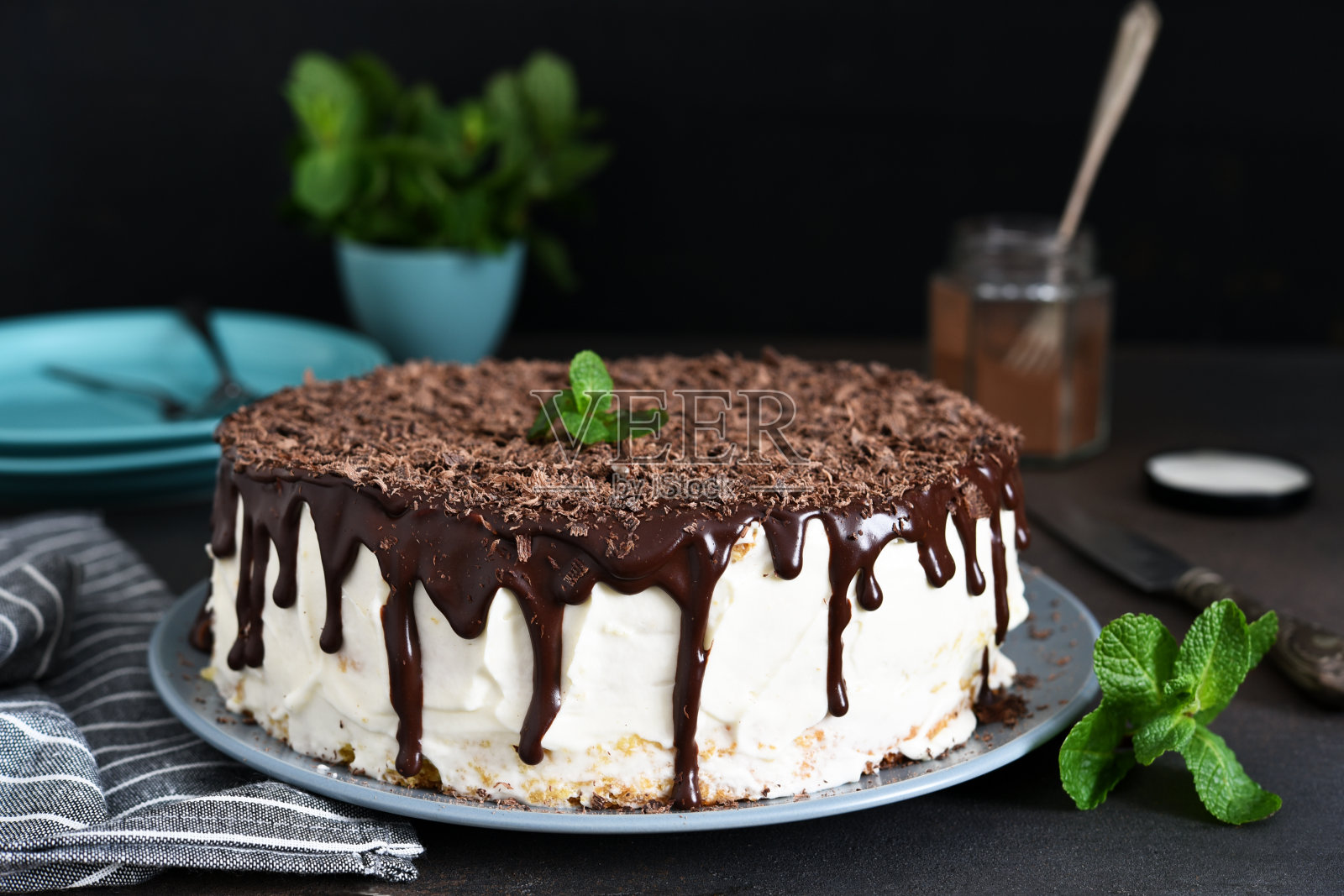 香草蛋糕与巧克力糖霜，巧克力片和薄荷在黑暗的背景。照片摄影图片