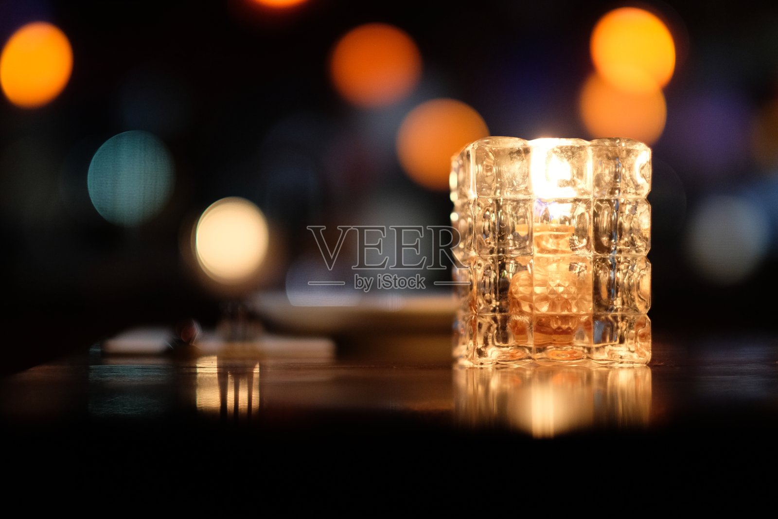 靠近桌上的玻璃蜡烛灯。照片摄影图片