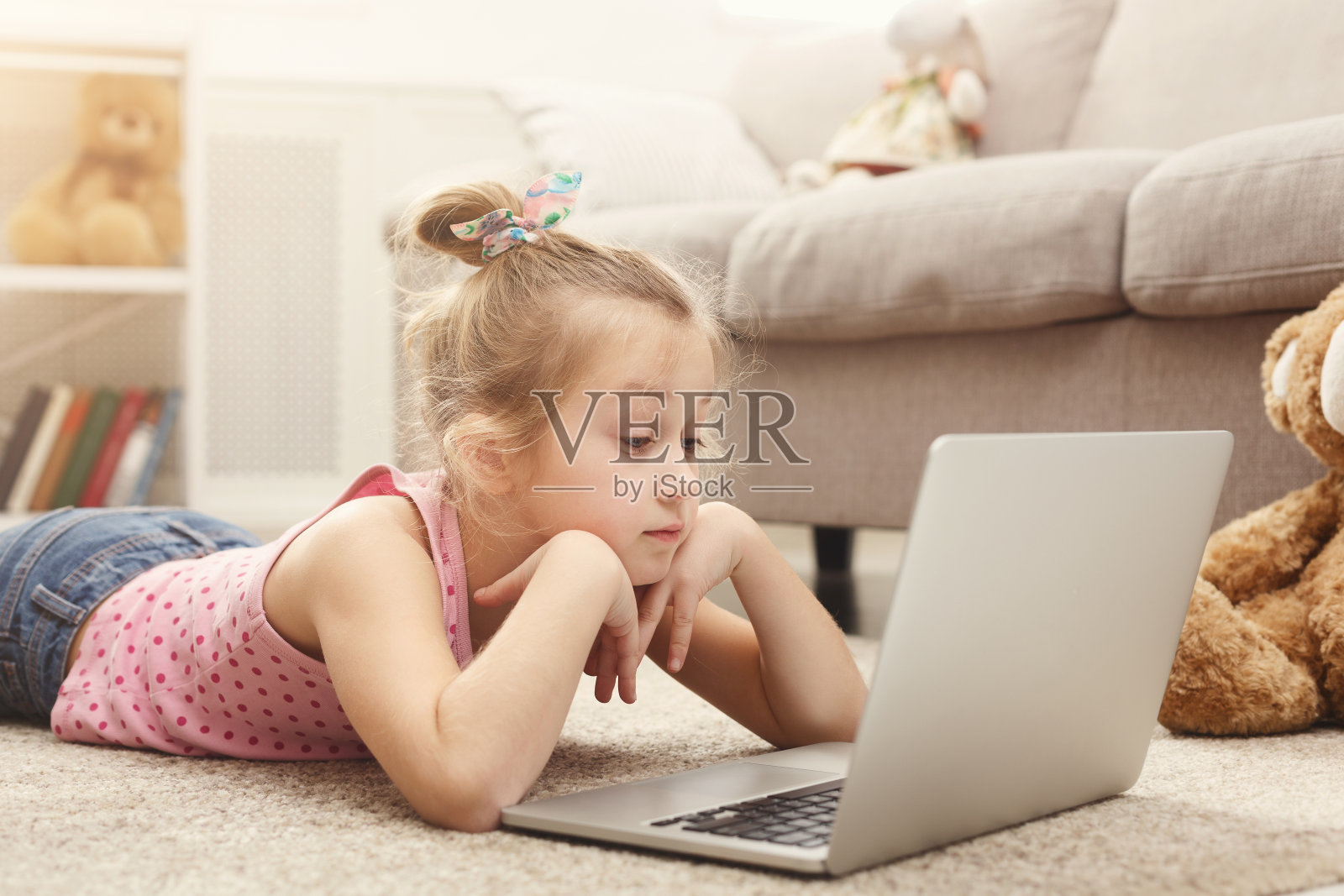 可爱的小女孩坐在家里的地板上用笔记本电脑做作业照片摄影图片