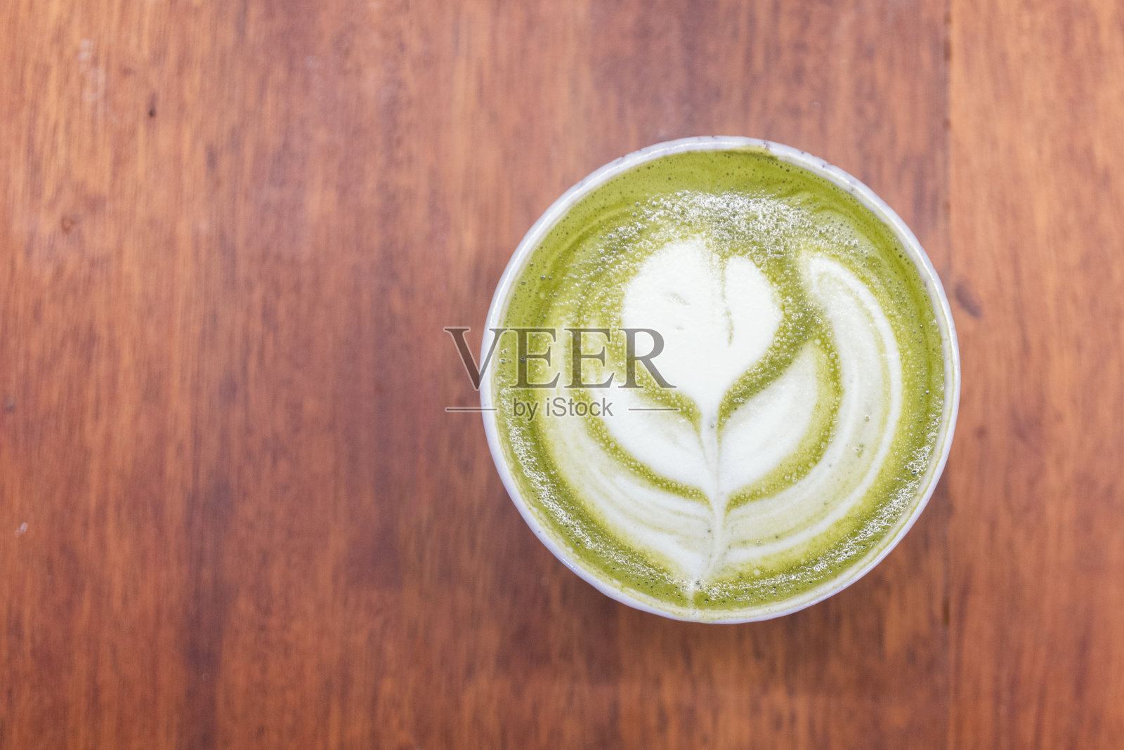 咖啡杯与绿色抹茶拿铁艺术泡沫在木桌上的咖啡店与复印空间。咖啡是最受欢迎的饮料之一。提高能量水平和燃烧脂肪照片摄影图片