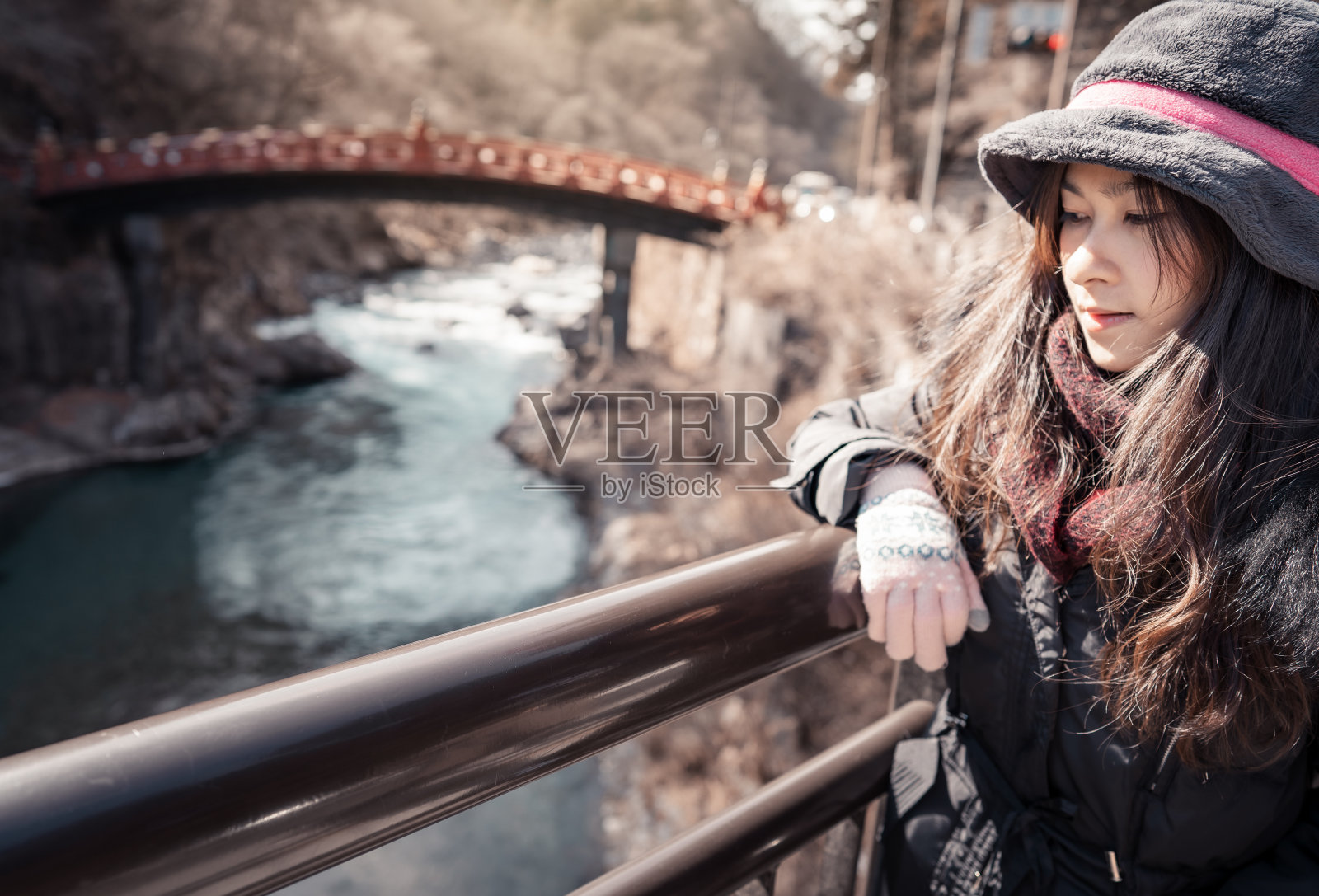 美丽的女子在日光市的村庄与红色木桥和水溪的观点在冬季照片摄影图片