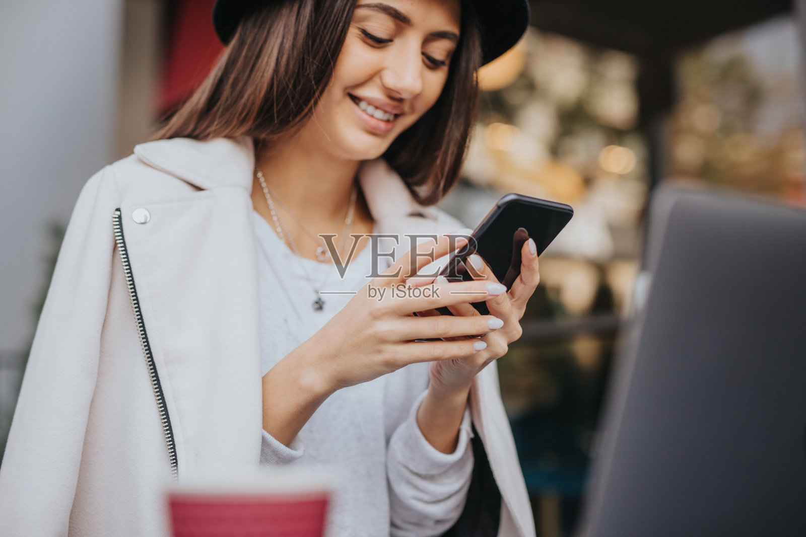 微笑的年轻女士在街头咖啡馆使用智能手机照片摄影图片