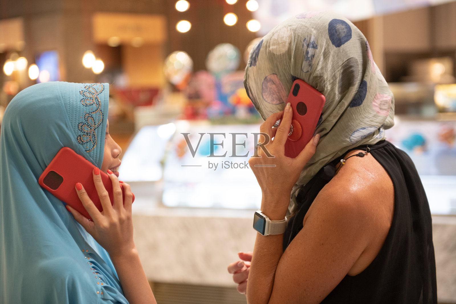 现代穆斯林。购物中心里拿着智能手机的穆斯林女性照片摄影图片