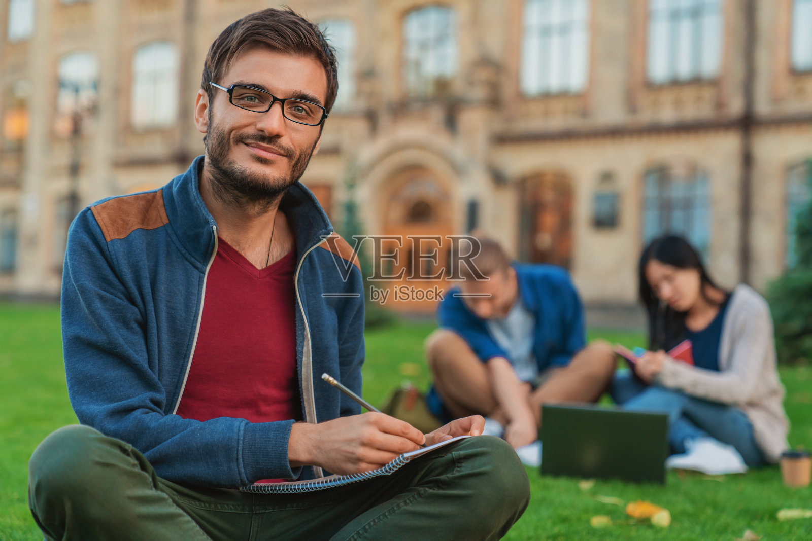 年轻男学生的肖像，当学生们在草坪上使用笔记本电脑时照片摄影图片