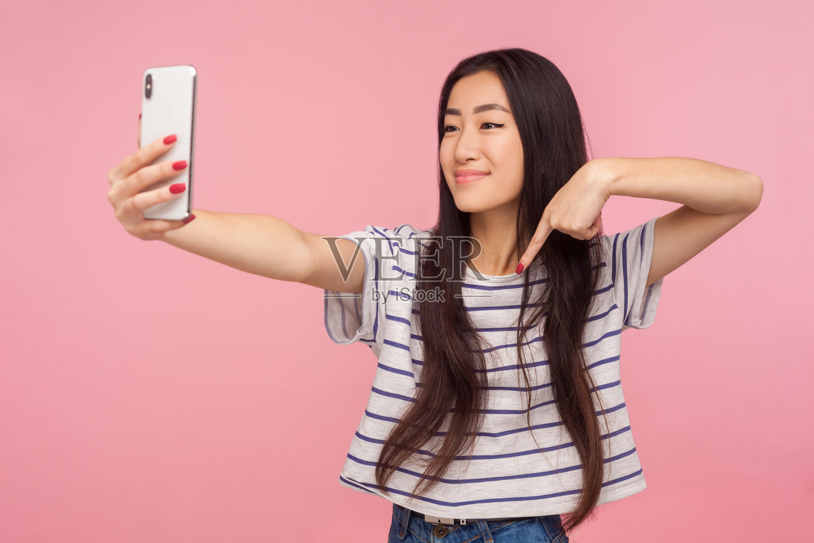 迷人的亚洲女孩的肖像与深色头发的手机自拍，在视频通话中交流照片摄影图片
