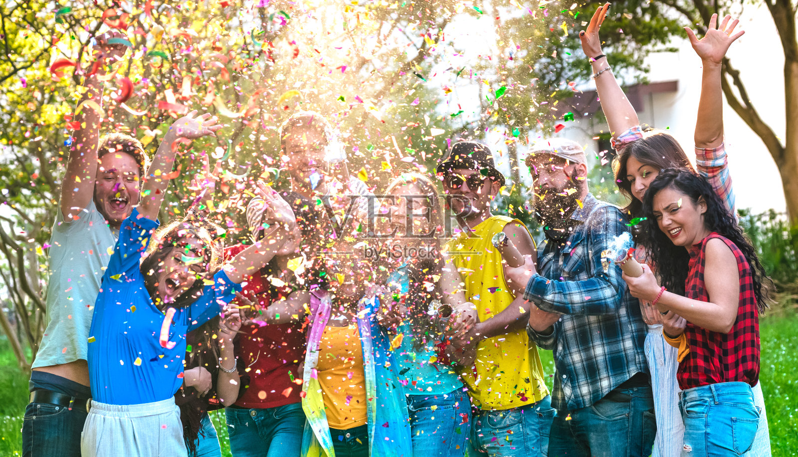快乐兴奋的朋友有乐趣的户外庆祝与五彩纸屑-年轻的千禧一代享受夏季一起在花园派对-愉快的友谊概念上温暖生动的过滤色调照片摄影图片
