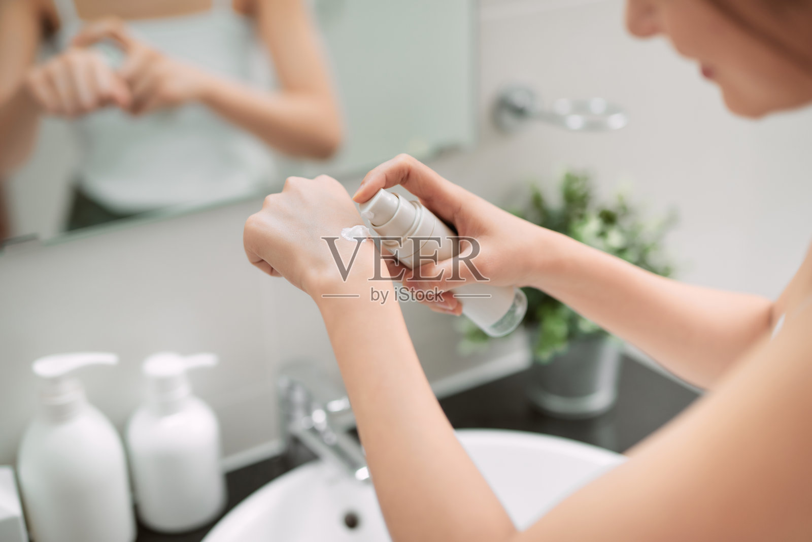 身体保健的概念。沐浴后在手上和指甲上涂抹保湿护手霜的女性。照片摄影图片