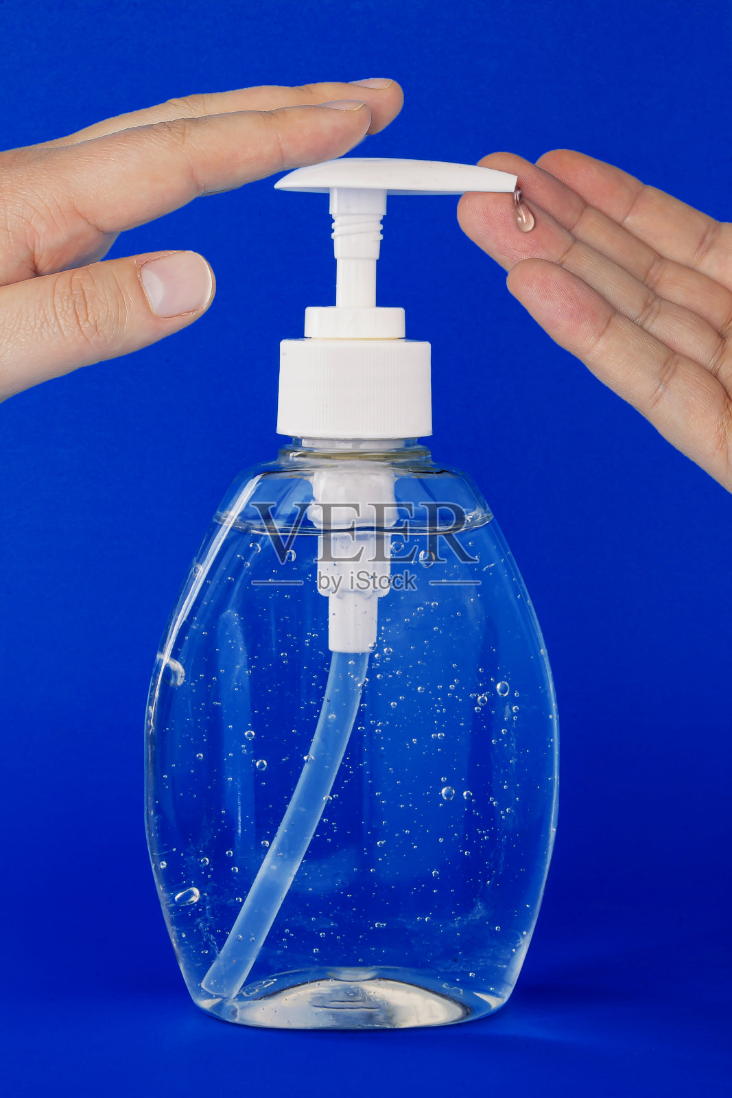 一个人在深蓝色的背景上使用洗手液的特写照片摄影图片