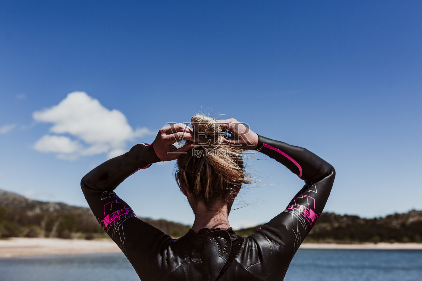 一个四十多岁的女人穿着氯丁橡胶，等着在湖里游泳。铁人三项的概念照片摄影图片