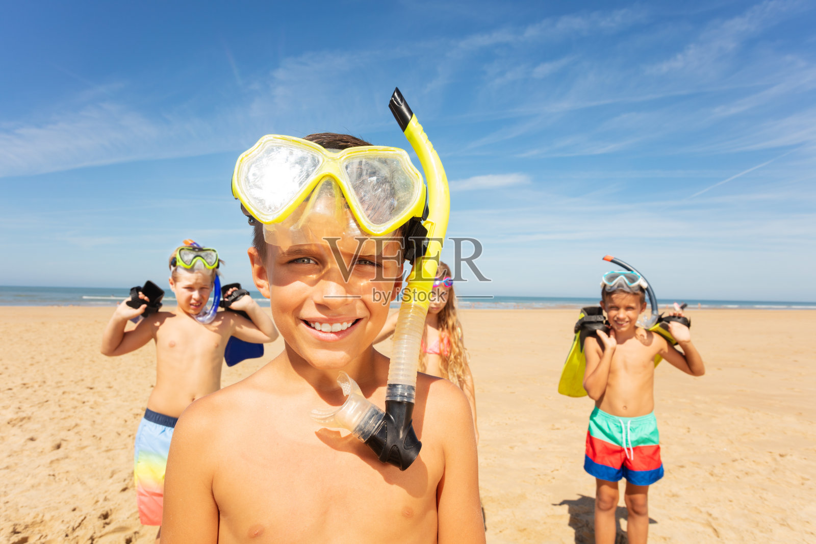 男孩戴着浮潜面具，一群朋友在海滩上照片摄影图片