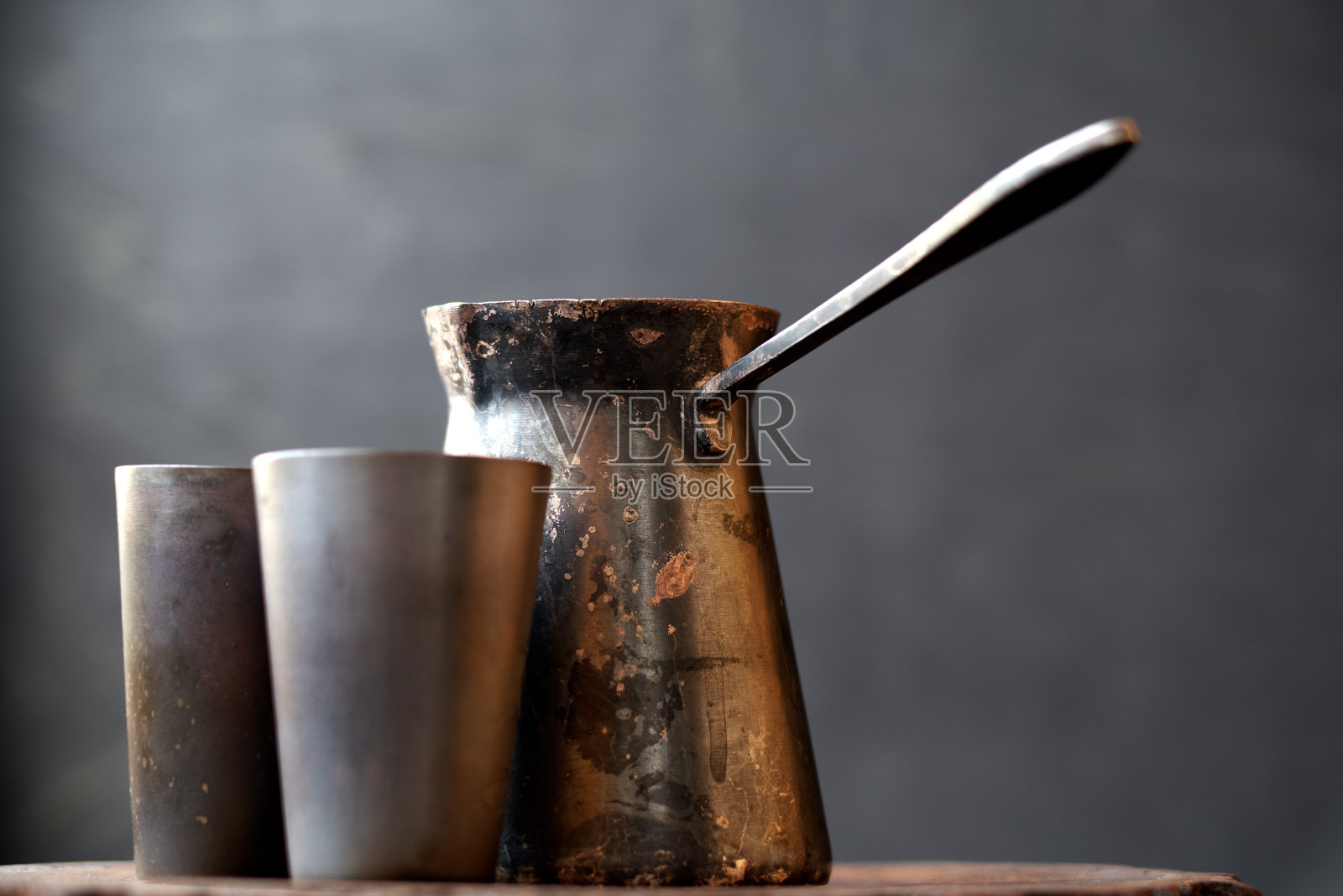 古董闪亮的铜土耳其咖啡壶和杯子上的深灰色背景下的黑色背景照片摄影图片