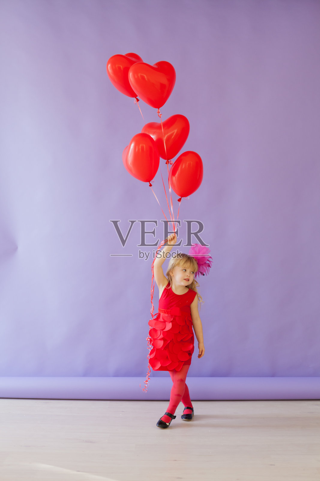 漂亮的女孩坐在红色心形气球上照片摄影图片