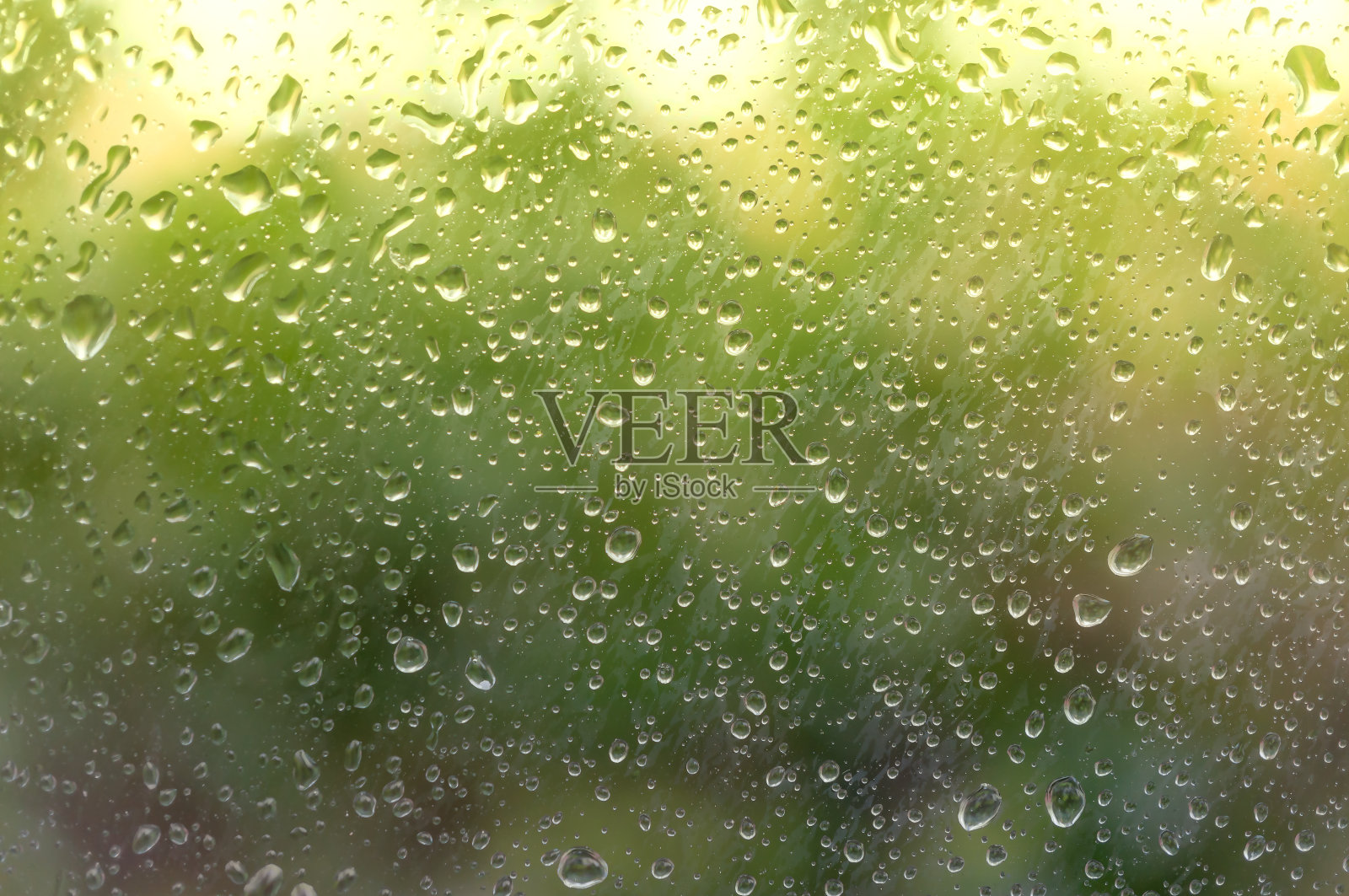 雨点落在雾蒙蒙的玻璃上，被坏天气后的第一缕阳光照亮。软的焦点。照片摄影图片