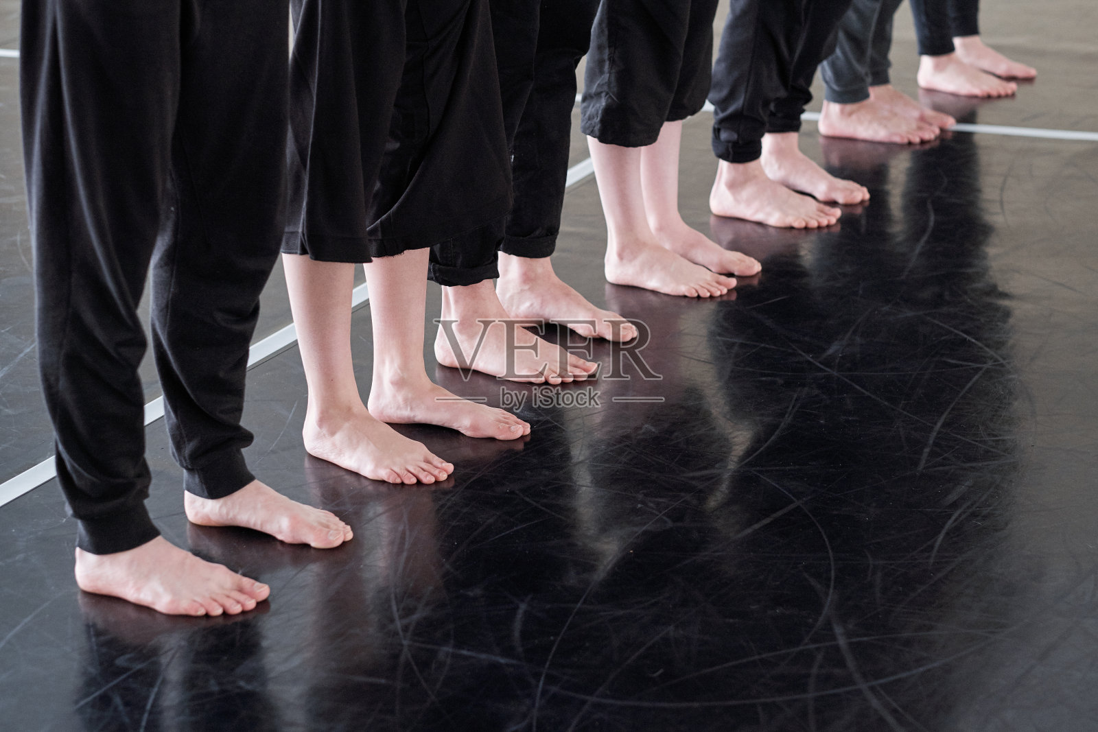 一排光脚的年轻舞者穿着黑色裤子站在地板上照片摄影图片