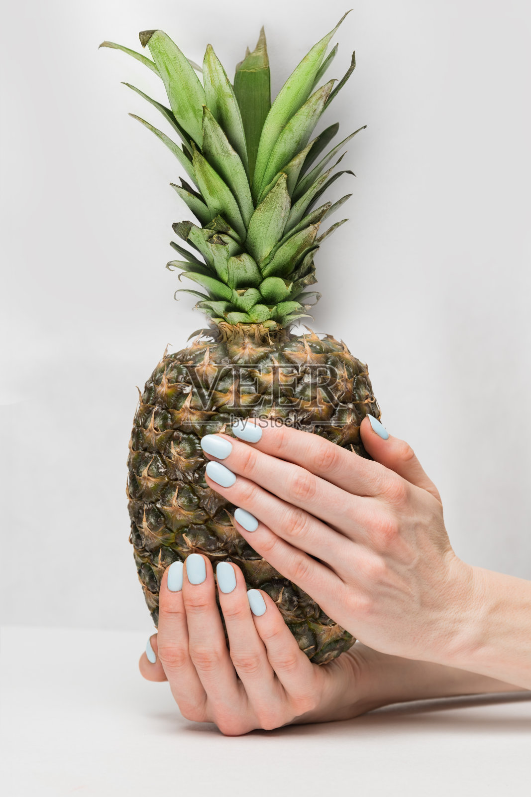 夏天修指甲。白底上拿着菠萝的女孩。垂直框架照片摄影图片
