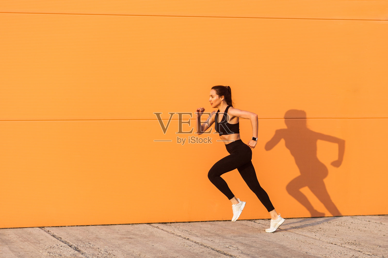 积极自信的健康女性运动员紧身运动服，黑色裤子和上衣，开始跑，慢跑户外照片摄影图片