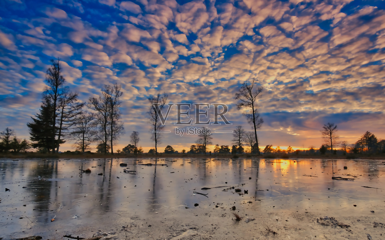 冬天寒冷的日落在冰冻的湖面上，美丽的天空和阳光在背景弗里斯兰，荷兰照片摄影图片