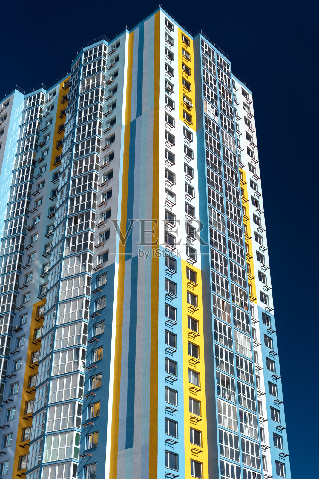 蓝天映衬下的现代多层住宅。色彩缤纷的高层住宅外墙。视图从下面照片摄影图片
