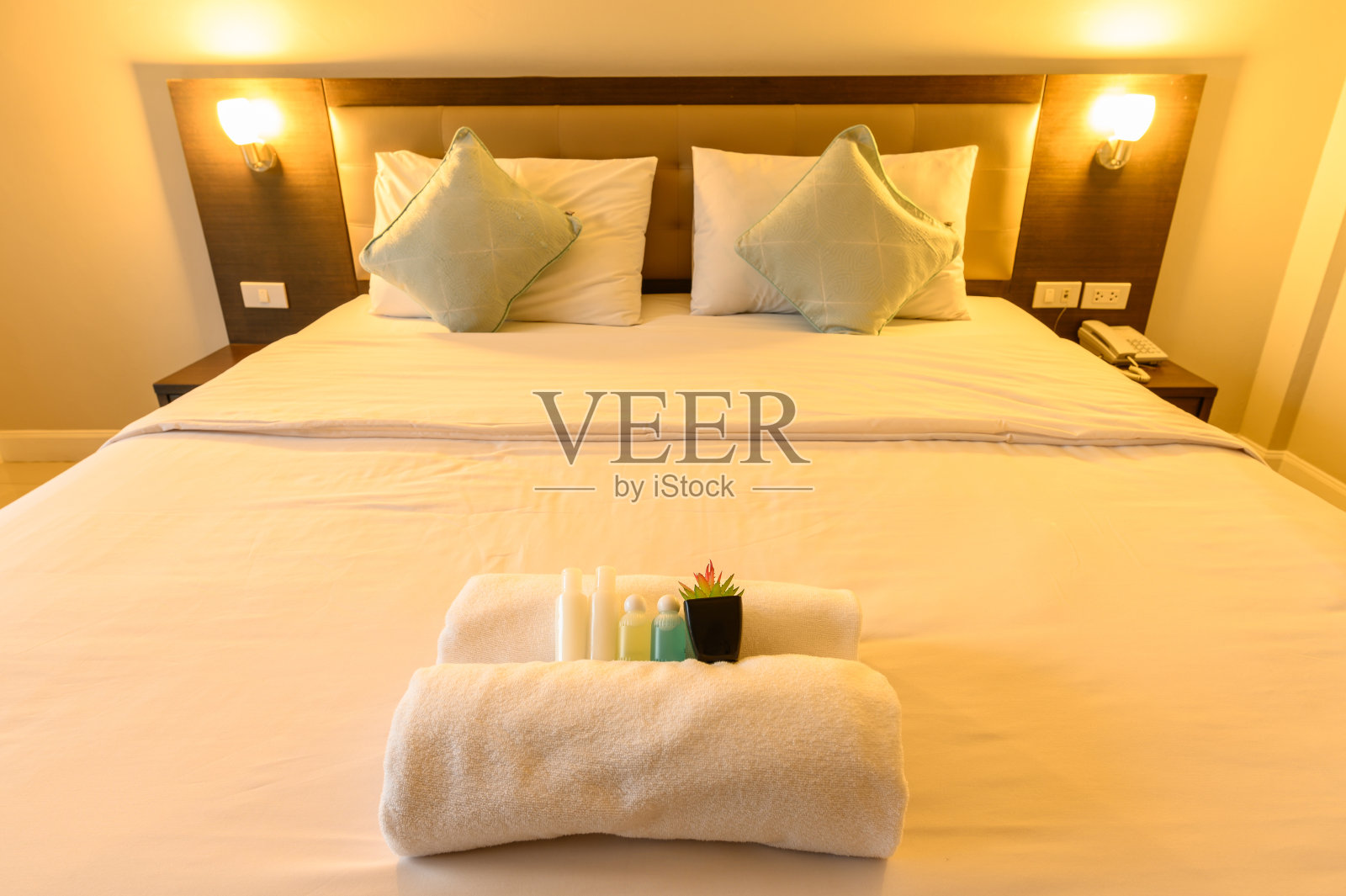 舒适的床和温暖的照明在酒店卧室装饰在舒适的风格(重点赠送物品)。照片摄影图片