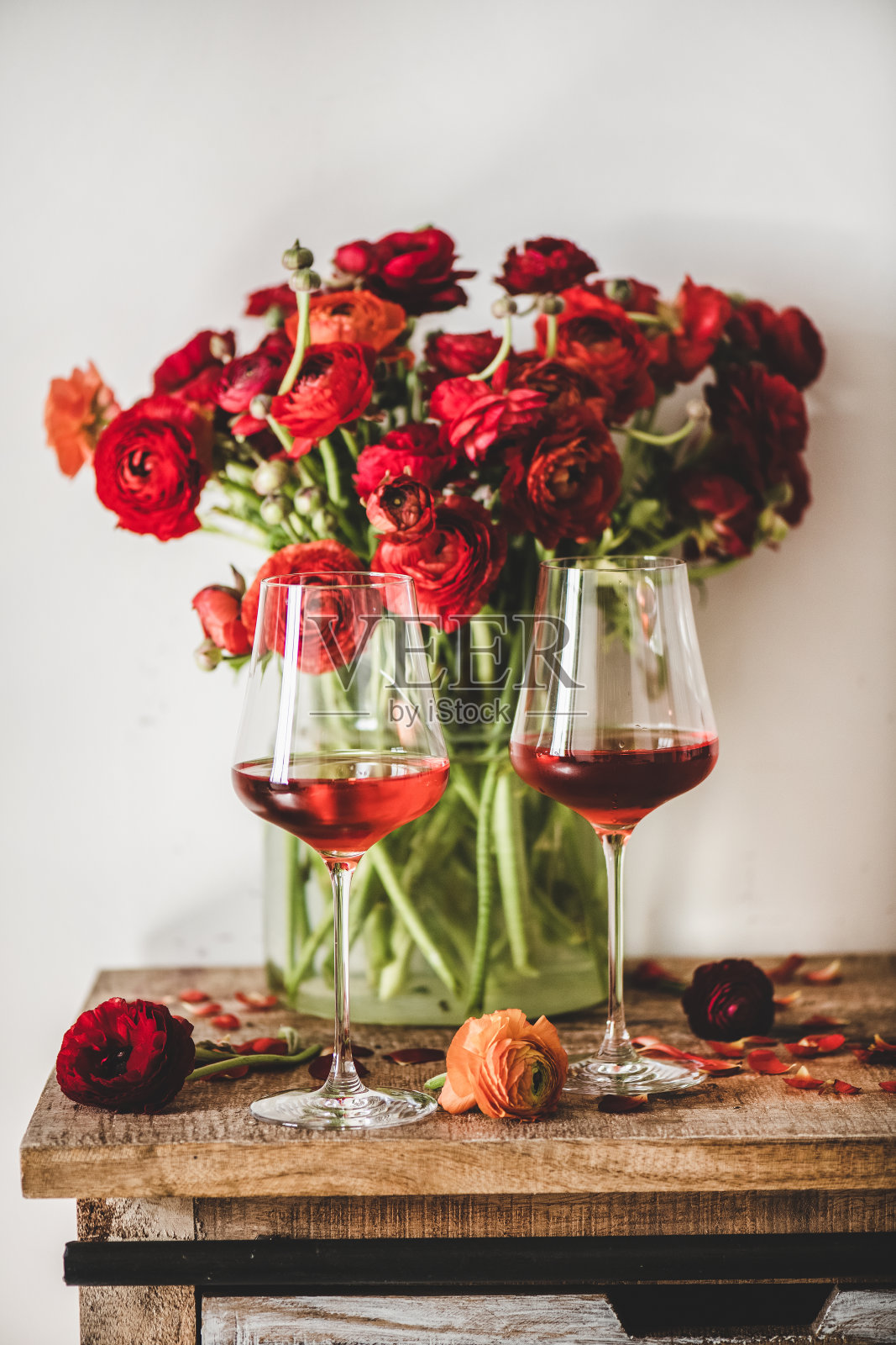 酒杯里盛着玫瑰酒，木桌上放着红花照片摄影图片