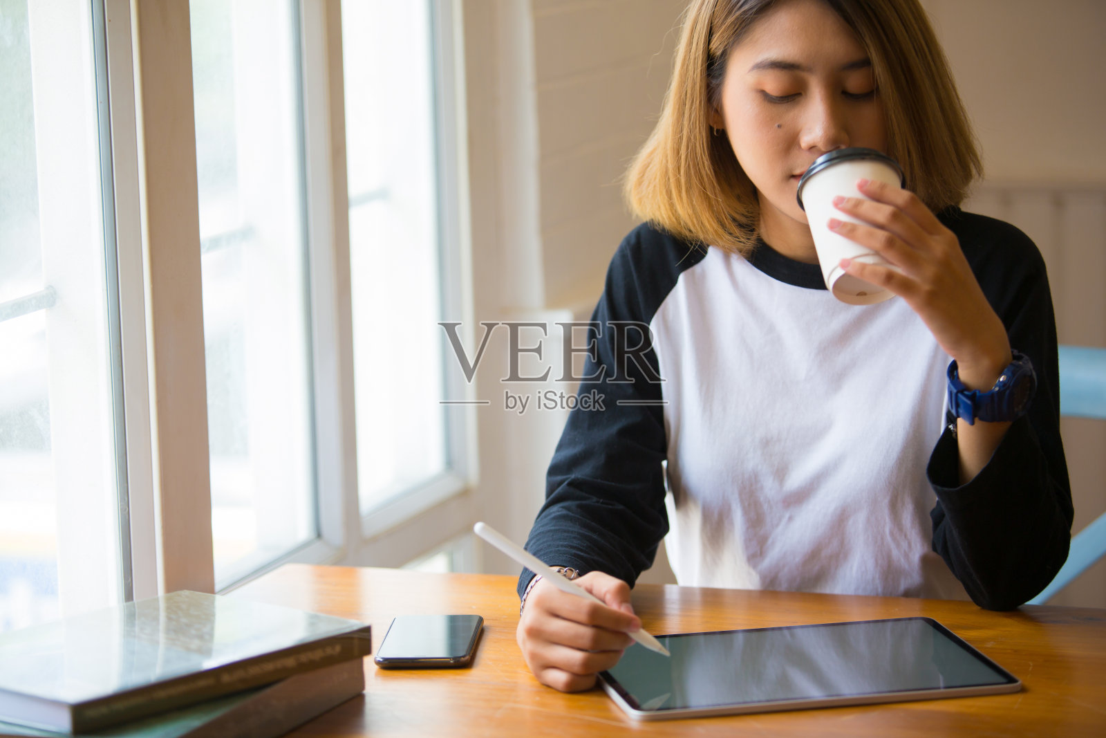 亚洲美丽的女人自由职业者与一个平板电脑在她的房子的窗户愉快地在早晨温暖的光照片摄影图片