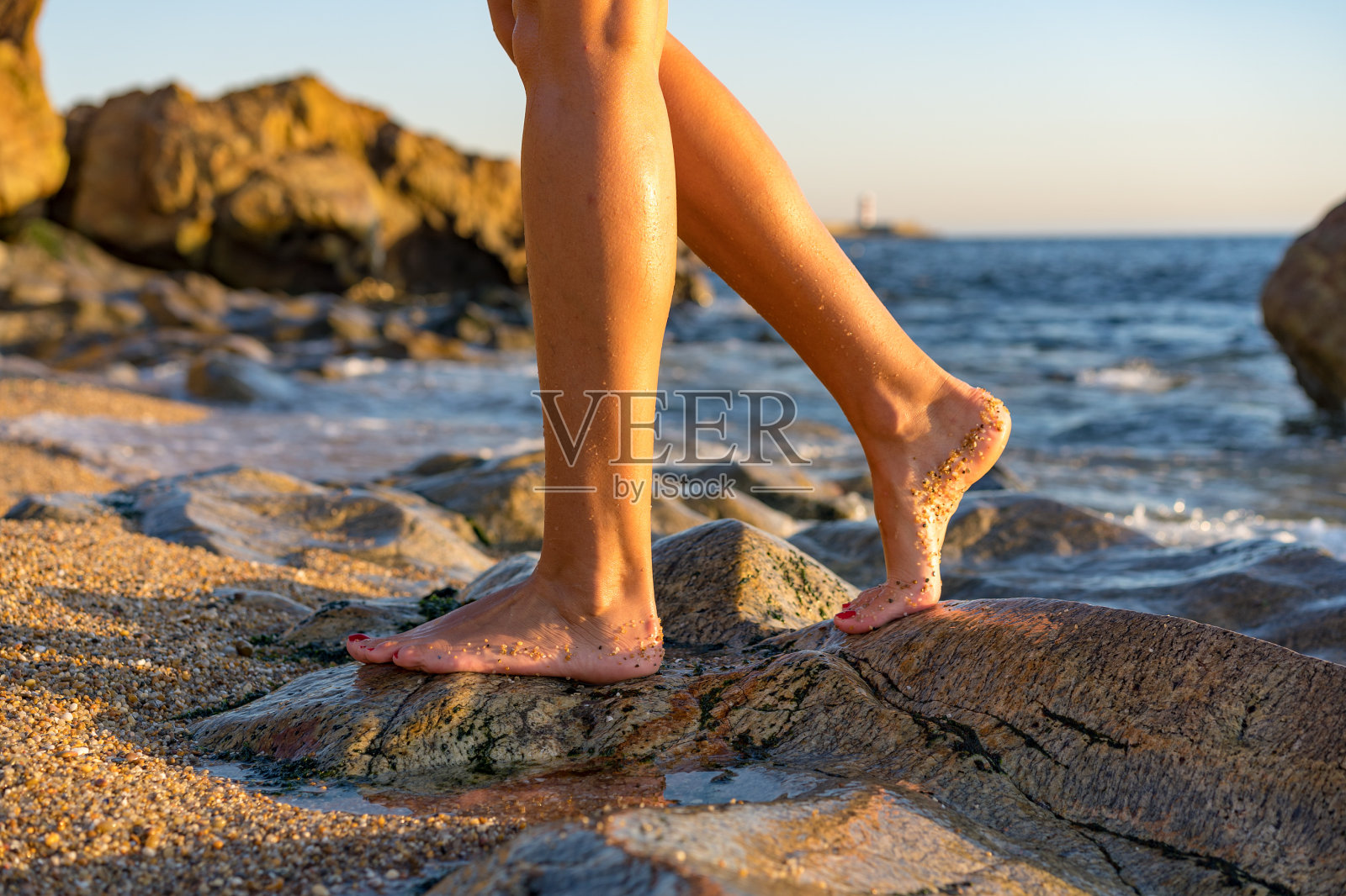 女人在海滩的岩石蘸脚趾水，有乐趣的户外生活方式在马托西尼奥斯，葡萄牙照片摄影图片