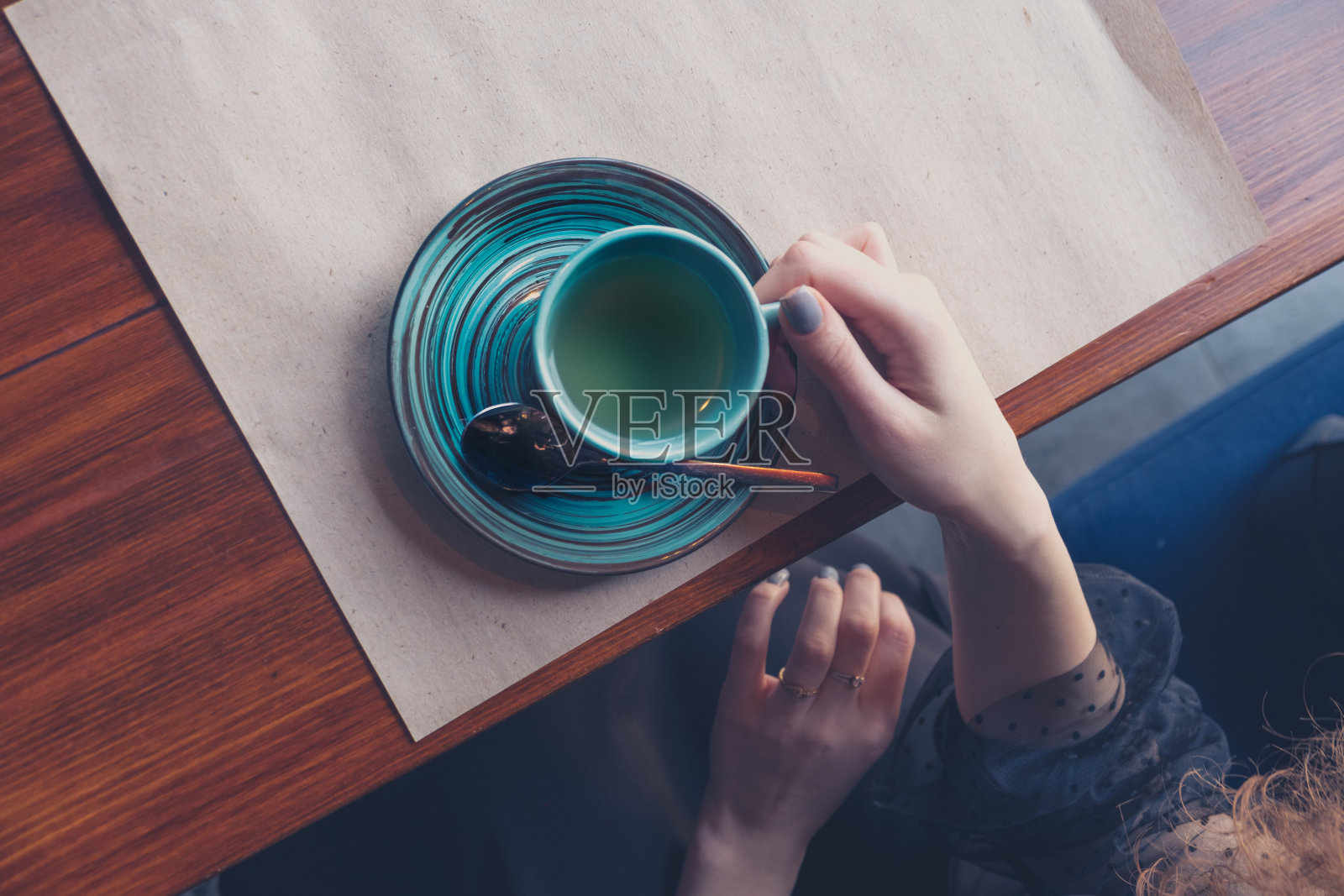 从上面看，桌上的女孩端着一杯咖啡，一个抄写空间照片摄影图片