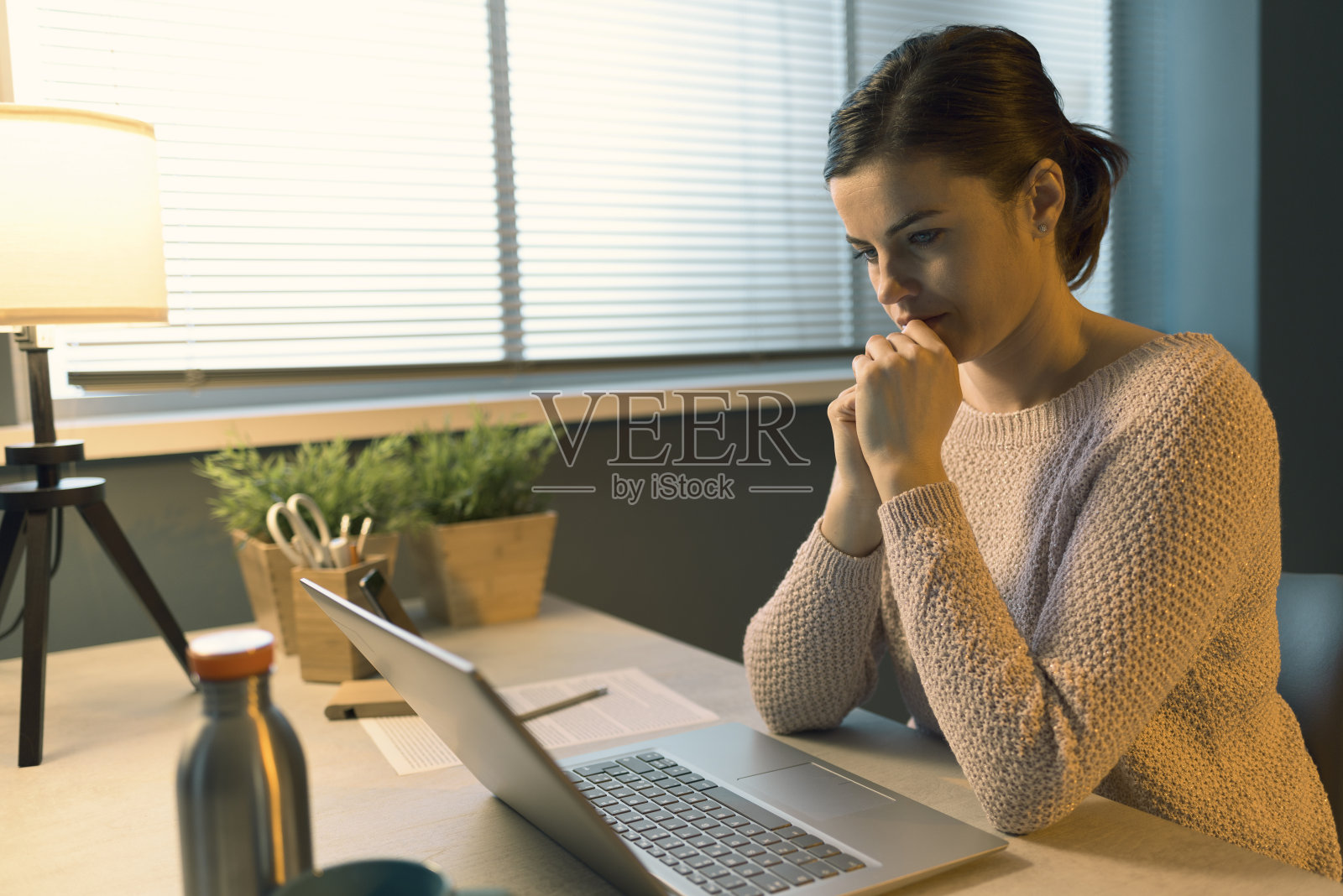 年轻女子坐在办公桌前使用笔记本电脑照片摄影图片