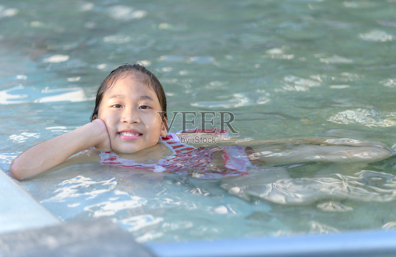 在游泳池里微笑的可爱小女孩照片摄影图片
