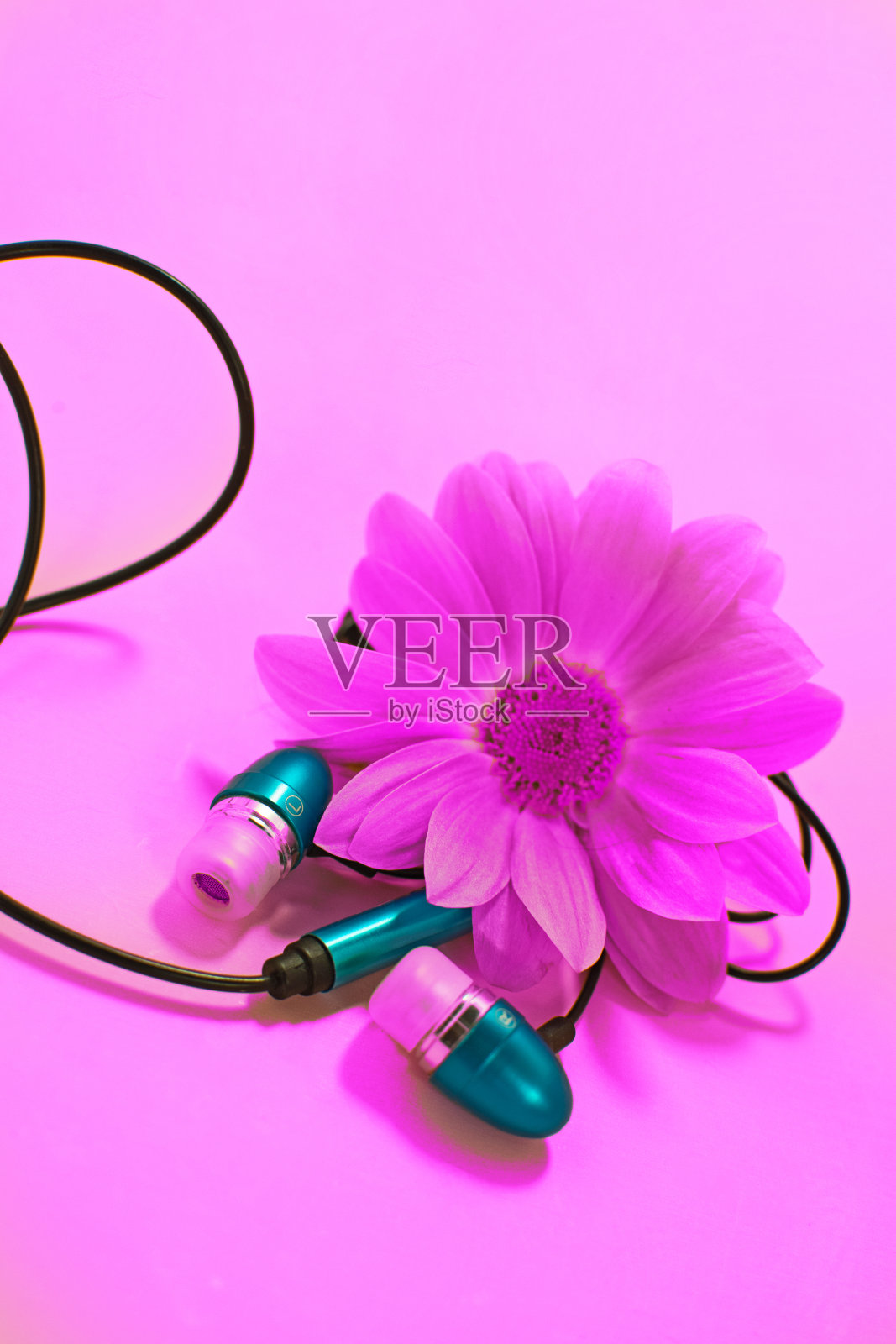 美丽的现代数字塑料真空蓝色耳机与电线听音乐在一个粉红色的背景。照片摄影图片