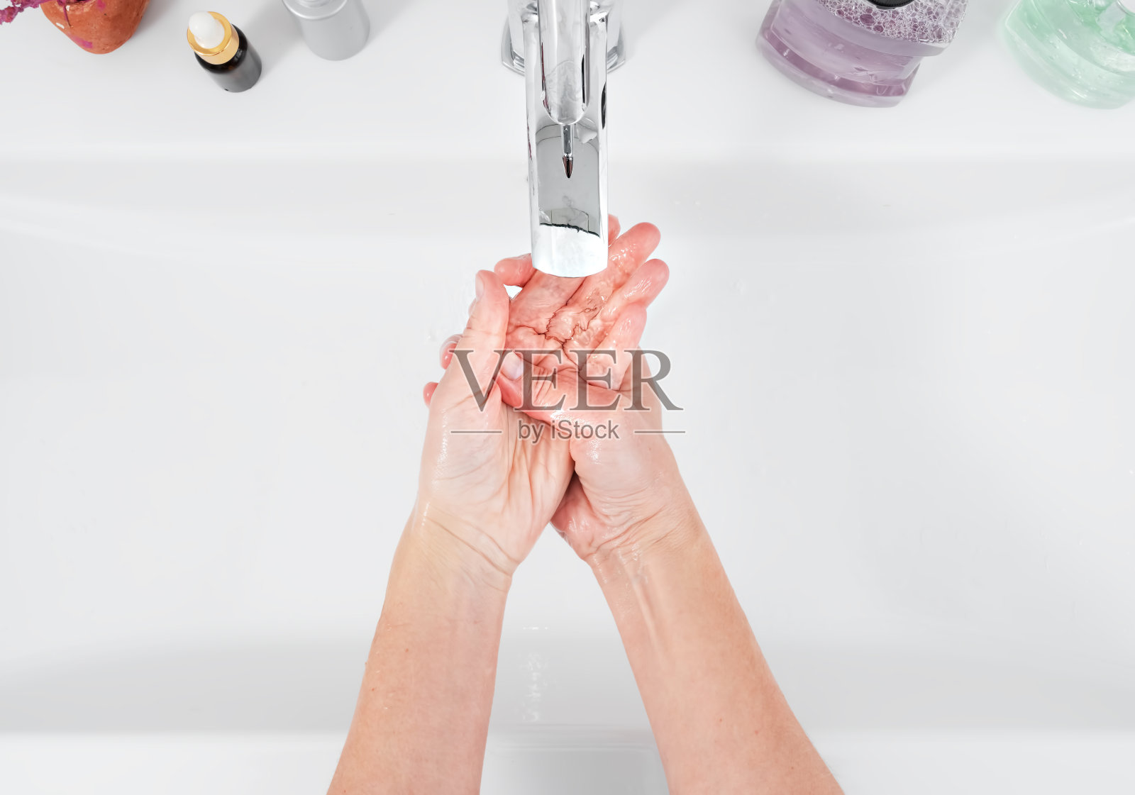 一位妇女在水龙头下洗手。卫生理念，俯视图，医疗保健。个人卫生和身体护理照片摄影图片